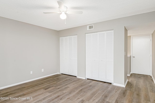 2145 Golf Isle Dr Unit 1212, Melbourne, FL 32935 - unfurnished bedroom featuring multiple closets, ceiling fan, a textured ceiling, and light wood-type flooring