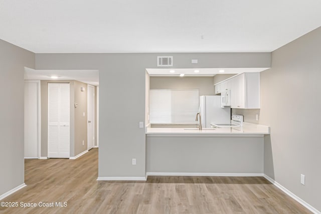 2145 Golf Isle Dr Unit 1212, Melbourne, FL 32935 - kitchen with sink, white cabinetry, light hardwood / wood-style flooring, kitchen peninsula, and white appliances