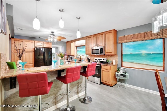 kitchen featuring pendant lighting, backsplash, a kitchen breakfast bar, ceiling fan, and stainless steel appliances