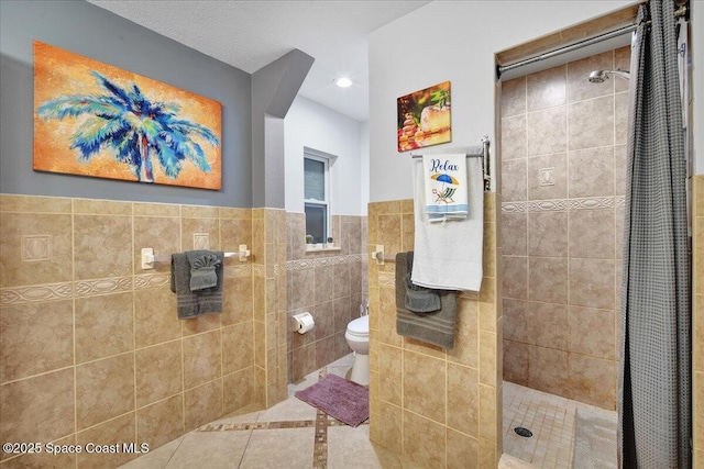 bathroom with toilet, tile patterned flooring, tile walls, and a tile shower