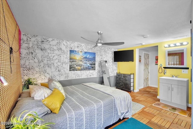 bedroom featuring light parquet floors, ceiling fan, sink, and a textured ceiling