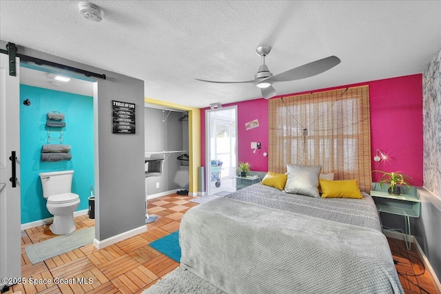 bedroom with ceiling fan, a textured ceiling, a barn door, a closet, and light parquet flooring