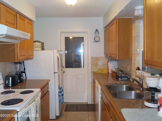 kitchen featuring sink, white appliances, light tile patterned floors, backsplash, and a textured ceiling