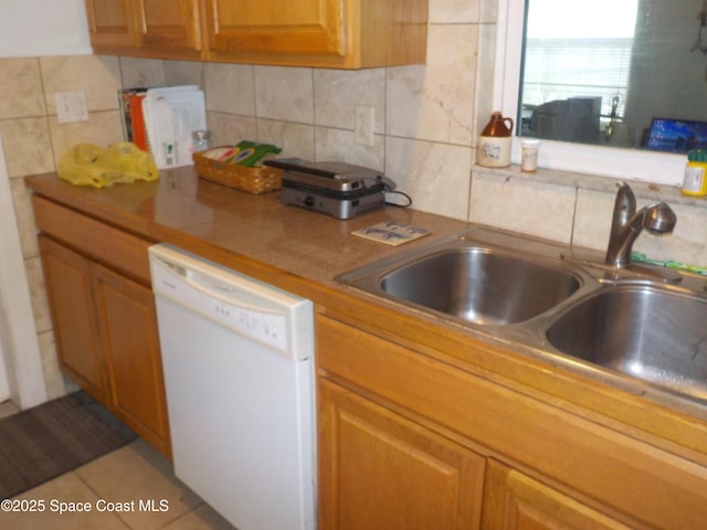 kitchen featuring tile patterned flooring, dishwasher, sink, and decorative backsplash