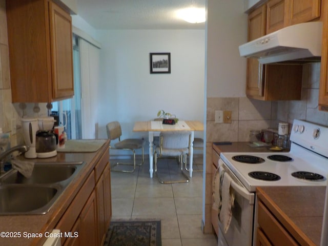 kitchen with backsplash, light tile patterned floors, sink, and electric range