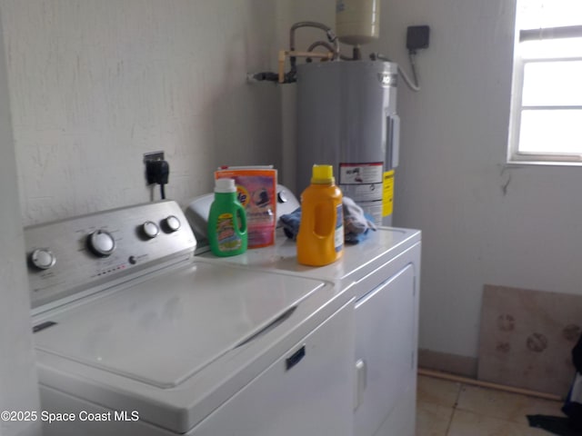 laundry area with electric water heater, washer and dryer, and light tile patterned floors