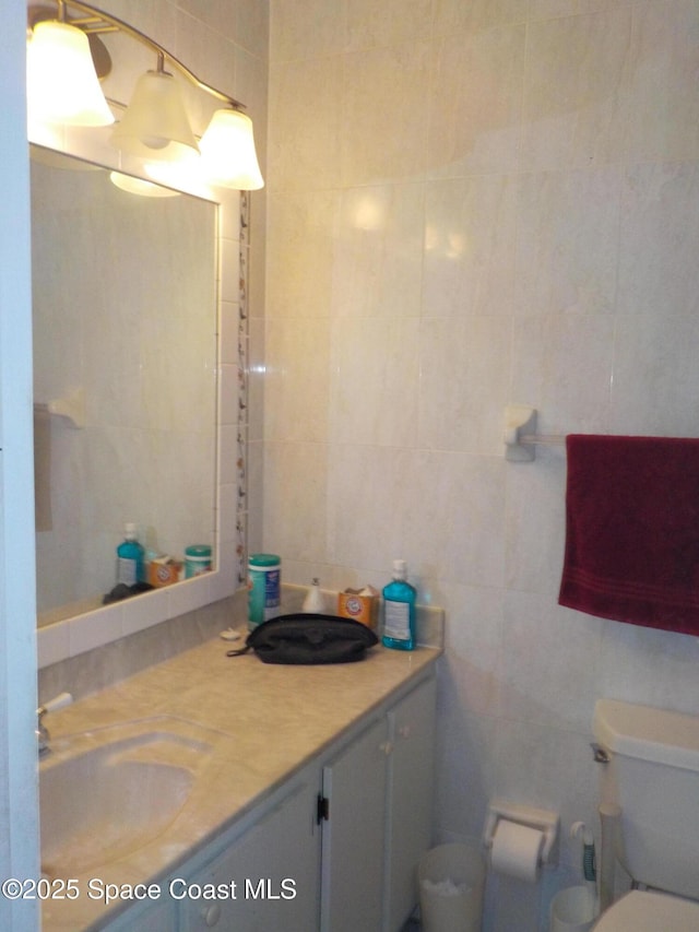 bathroom featuring vanity, tile walls, and toilet