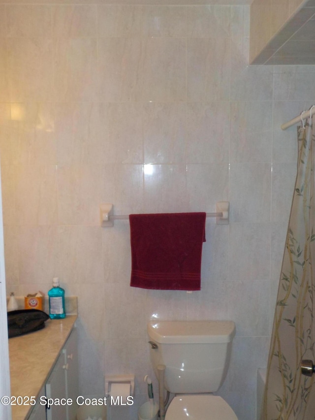 bathroom featuring tile walls, toilet, and shower / bath combo with shower curtain