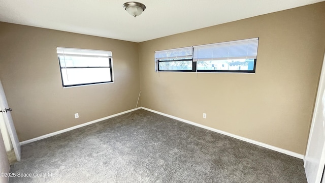 empty room with dark colored carpet and baseboards