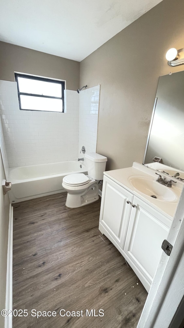 bathroom with toilet,  shower combination, wood finished floors, and vanity