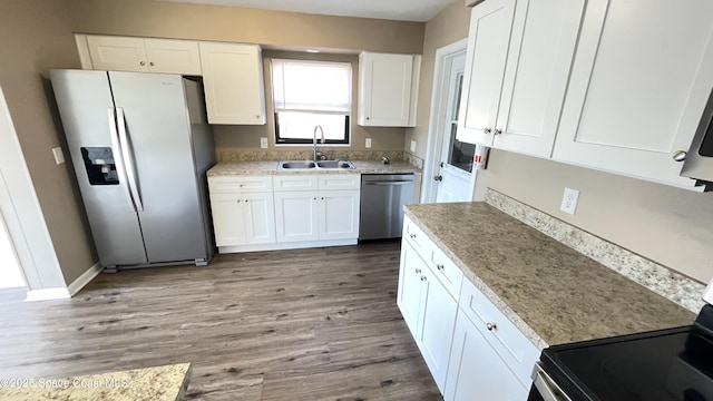 kitchen with light wood-style flooring, appliances with stainless steel finishes, white cabinets, and a sink