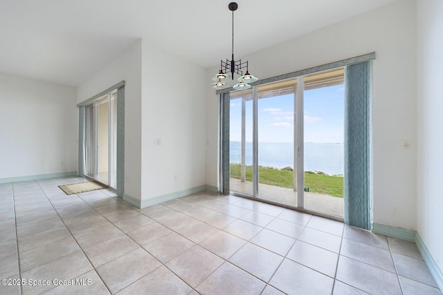 empty room with a water view, baseboards, and light tile patterned floors