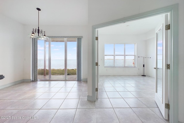 unfurnished dining area with light tile patterned floors, a water view, and baseboards