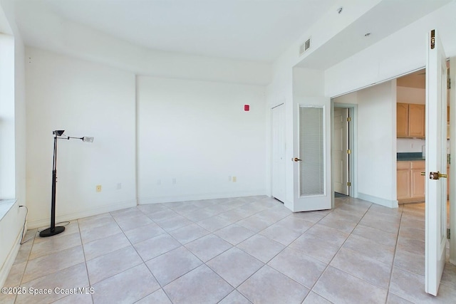 empty room with light tile patterned floors, baseboards, and visible vents