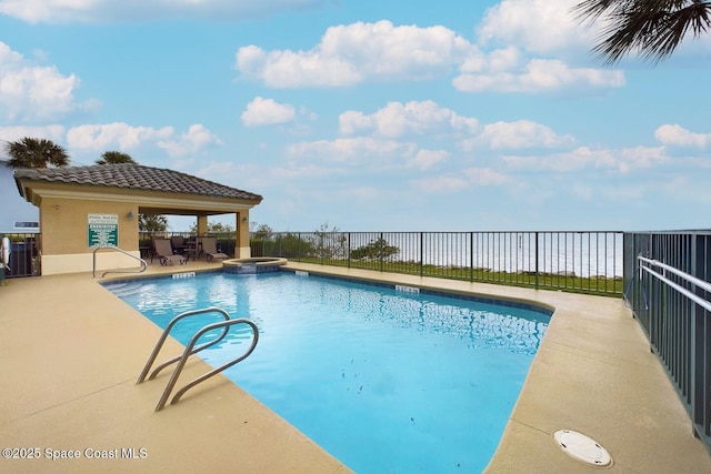 view of pool with a patio, fence, and a pool with connected hot tub