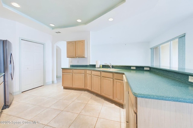 kitchen with light tile patterned floors, recessed lighting, light brown cabinetry, a sink, and stainless steel fridge