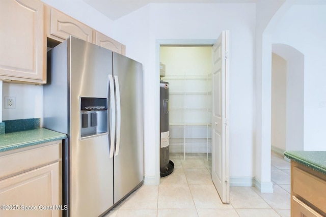 kitchen featuring arched walkways, stainless steel fridge with ice dispenser, electric water heater, light brown cabinets, and light tile patterned flooring