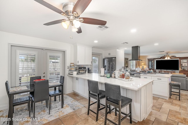 230 Andros Dr, Merritt Island, FL 32952 - kitchen with white cabinetry, appliances with stainless steel finishes, a kitchen breakfast bar, kitchen peninsula, and island exhaust hood