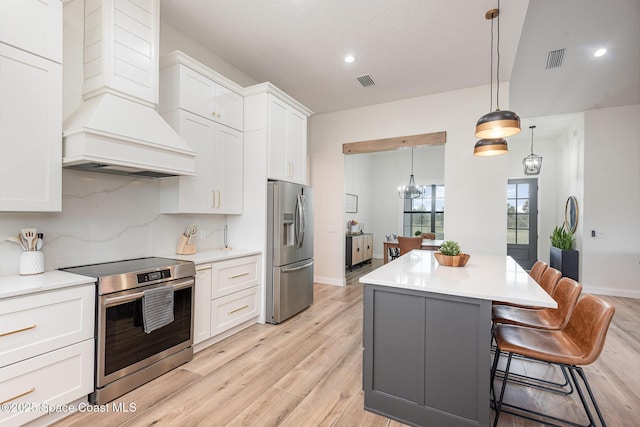 kitchen featuring white cabinetry, stainless steel appliances, a center island, custom range hood, and decorative light fixtures