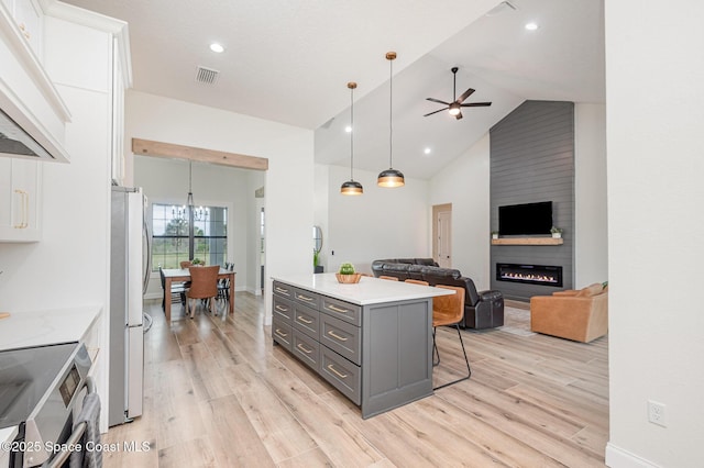 kitchen with white cabinetry, appliances with stainless steel finishes, a kitchen bar, and decorative light fixtures