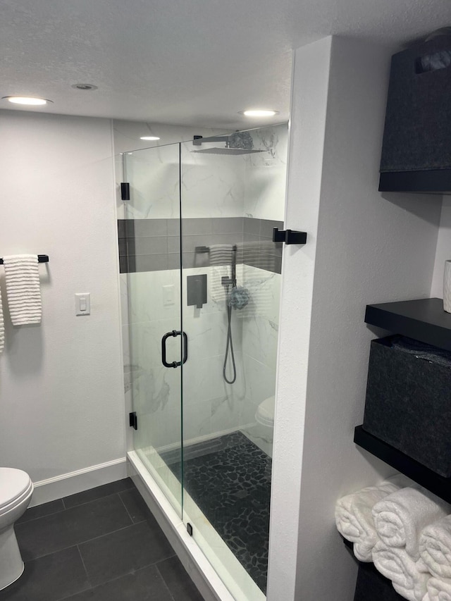 bathroom with a textured ceiling, a shower with shower door, tile patterned floors, and toilet