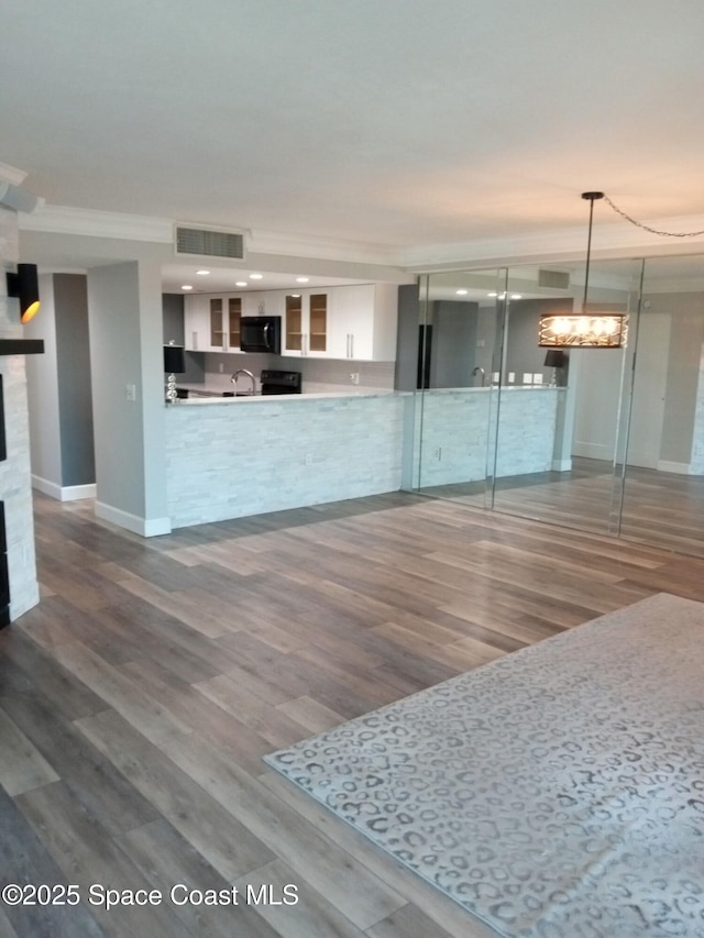 kitchen with sink, crown molding, white cabinetry, wood-type flooring, and decorative light fixtures