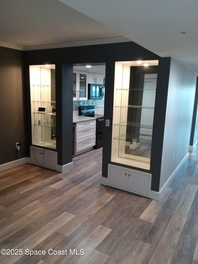 corridor featuring hardwood / wood-style flooring, lofted ceiling, and ornamental molding