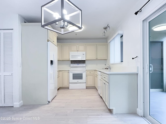 kitchen with an inviting chandelier, decorative light fixtures, sink, white appliances, and light wood-type flooring