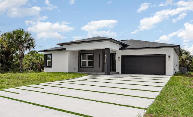 prairie-style home featuring a garage, central AC, and a front lawn