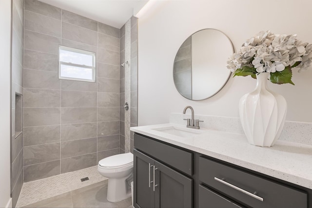 bathroom featuring tiled shower, vanity, toilet, and tile patterned flooring