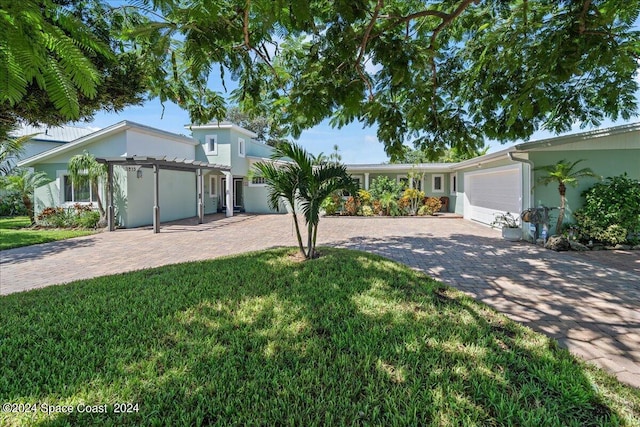 view of front of house with a garage, a front yard, decorative driveway, and stucco siding