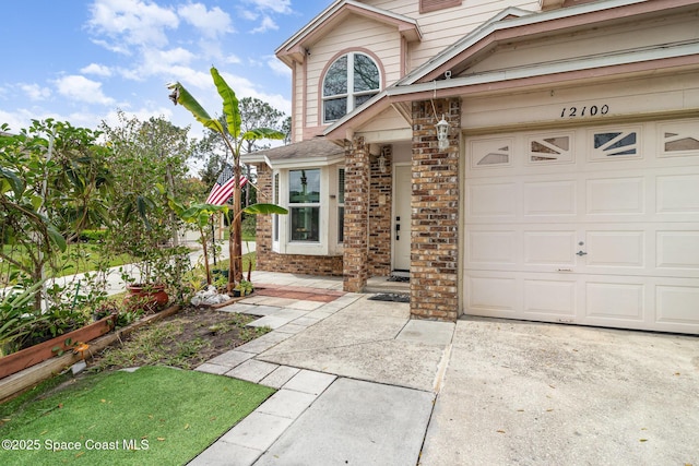 property entrance featuring a garage, concrete driveway, and brick siding