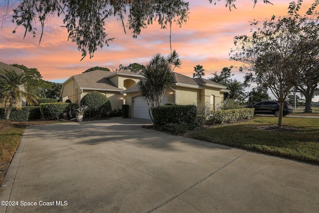 view of front of house featuring stucco siding, an attached garage, and driveway