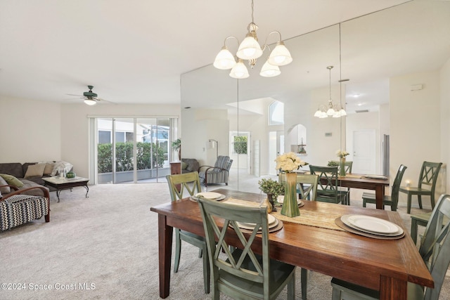 dining space with ceiling fan with notable chandelier and light carpet