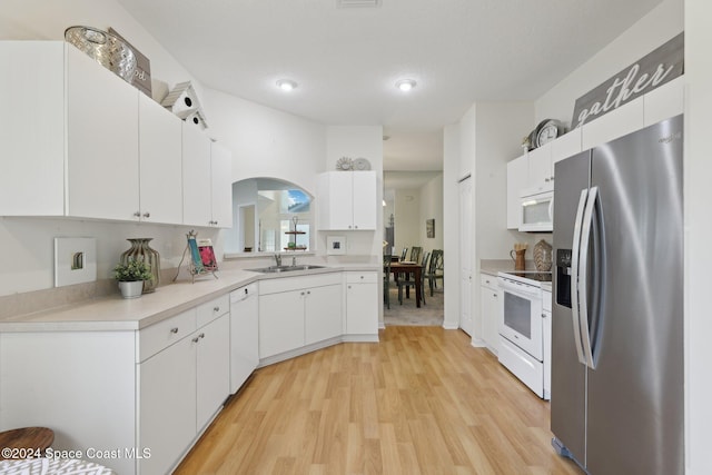 kitchen featuring light countertops, white cabinetry, light wood finished floors, and white appliances