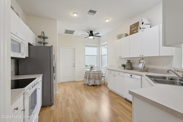 kitchen with a sink, visible vents, light countertops, white cabinetry, and white appliances