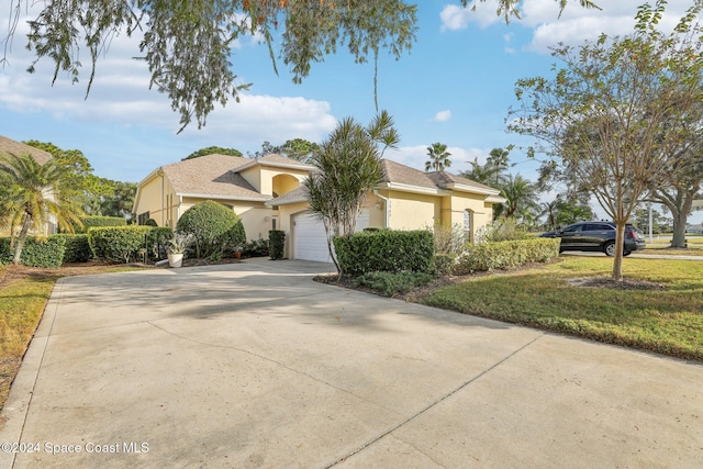 view of front of property with stucco siding, an attached garage, driveway, and a front lawn