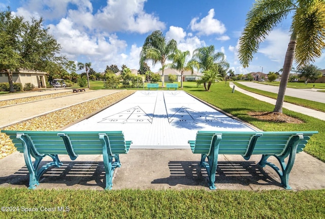 view of community with a lawn and shuffleboard