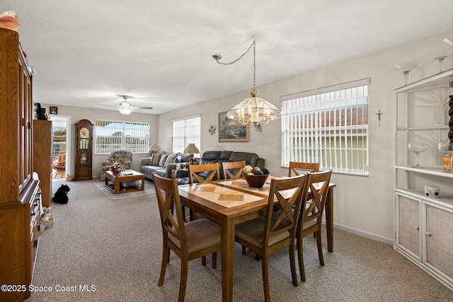 carpeted dining space featuring baseboards and ceiling fan with notable chandelier