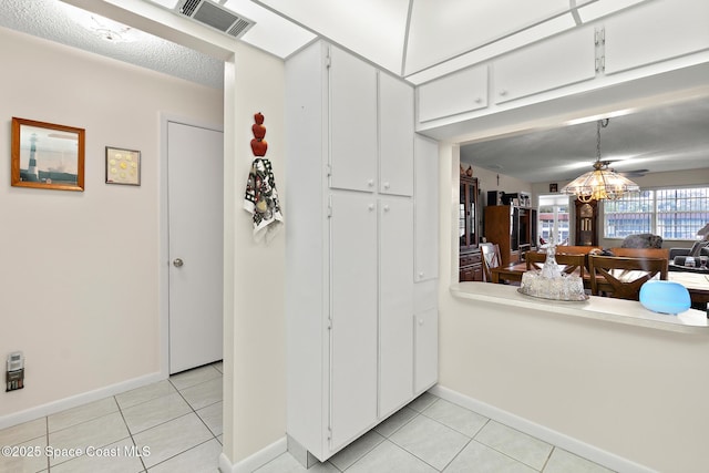 interior space with light tile patterned floors, light countertops, visible vents, and white cabinets