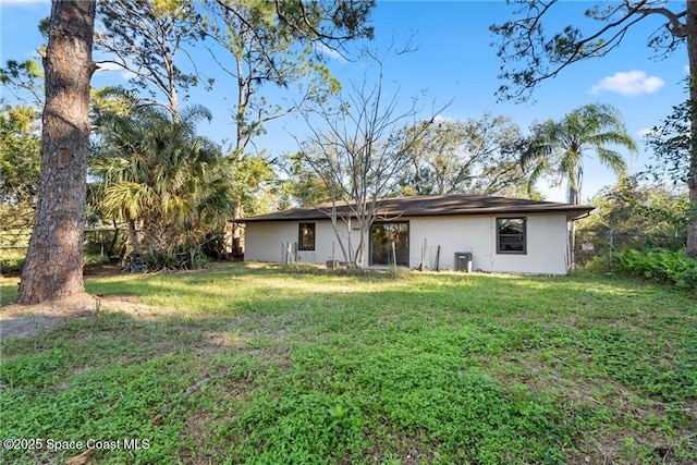 rear view of property featuring a yard and central air condition unit