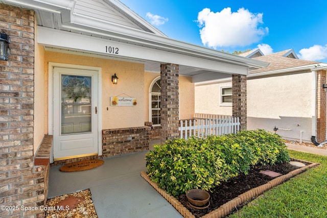 doorway to property with brick siding and stucco siding