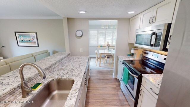 kitchen with a sink, a textured ceiling, dark wood finished floors, stainless steel appliances, and white cabinets