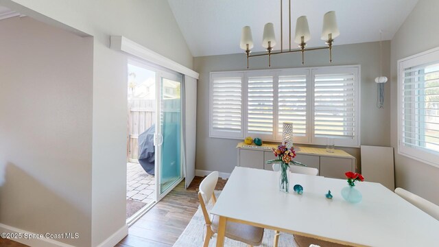 dining space featuring baseboards, wood finished floors, and vaulted ceiling