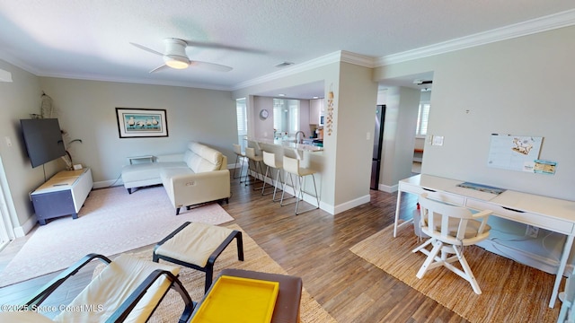 living area featuring visible vents, crown molding, baseboards, and wood finished floors