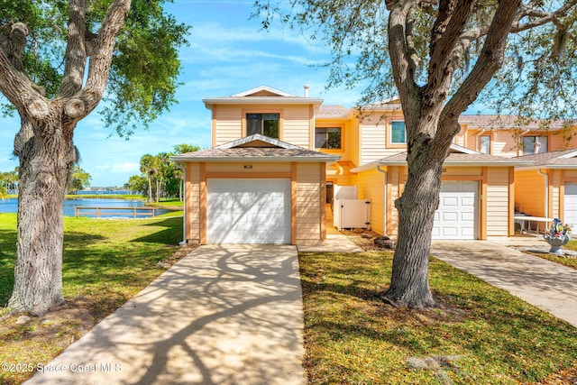 view of property featuring a garage, a shingled roof, concrete driveway, a water view, and a front lawn