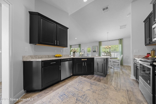 kitchen with sink, hanging light fixtures, light wood-type flooring, kitchen peninsula, and stainless steel appliances