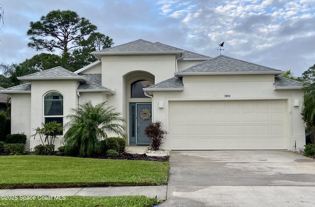 view of front of property with a garage, concrete driveway, a front lawn, and stucco siding