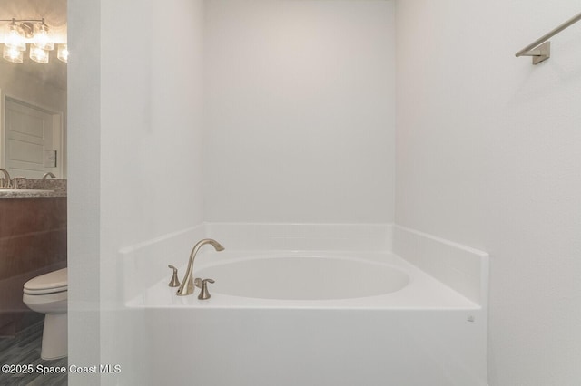 bathroom featuring vanity, a tub, and toilet