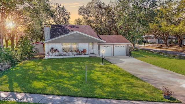 view of front of house featuring an attached garage, a chimney, concrete driveway, and a front yard